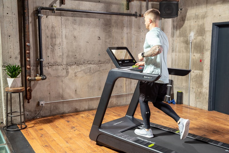 Person using a treadmill in a gym setting.