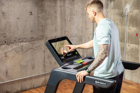 Man using a treadmill with an operating console inside a room.