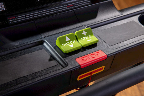 A treadmill displaying a green and red button on its control panel.