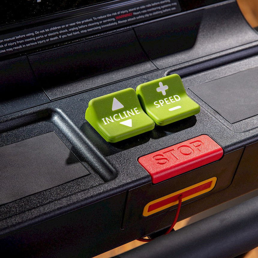 A treadmill displaying a green and red button on its control panel.