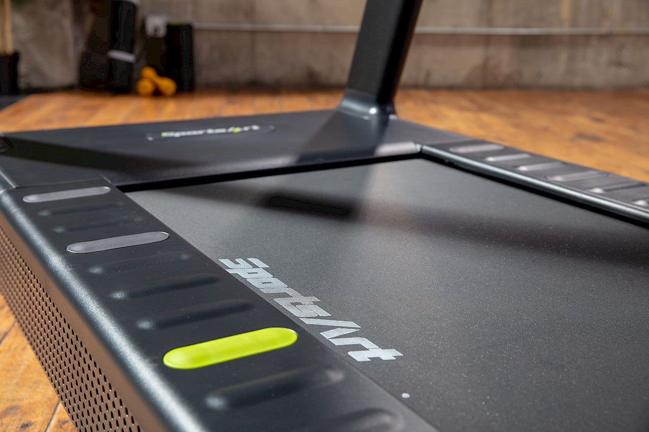 A treadmill set on the gym floor reading for using.